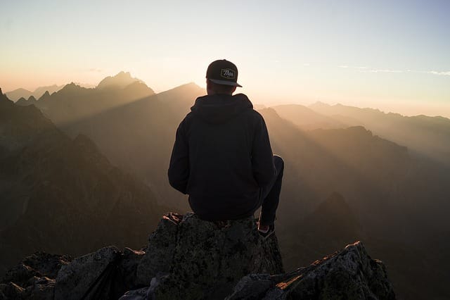 Person sitting on a mountain top at sunrise